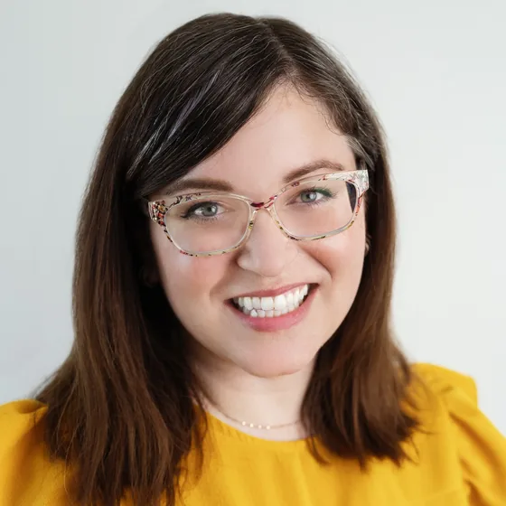 Corrie Verheijen, smiling, in patterned glasses and a golden top